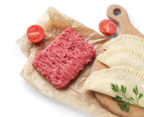 Board with raw chebureks, baking paper, mince and cut tomato on white background