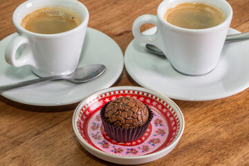 Brigadeiro (Brigadier) a Brazilian chocolate candy. Traditional Brazilian handmade chocolate sweet on top of a colorful plate and a white ceramic coffee cup in the background.