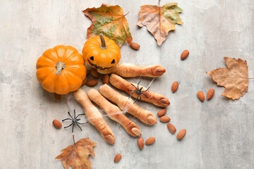 Halloween cookies with almond nuts, pumpkins and fallen leaves on light background