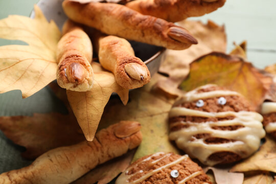 Halloween cookies with fallen leaves on green wooden background, closeup