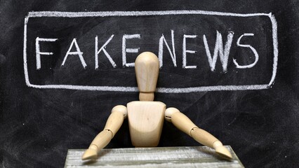 Muñeco articulado de madera sentado a modo de presentador de noticias falsas, fake news