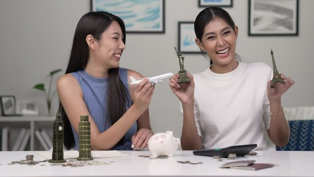 Young Asian lesbian couple plans to save money for a trip around the world. Travel budget concept. passport, monument model and aircraft toy in the picture. Lgbt couple lifestyle.