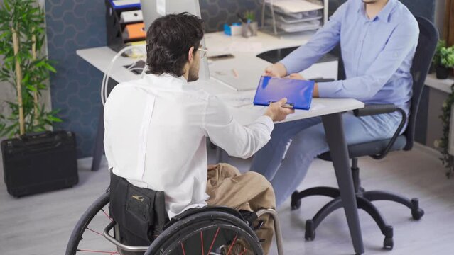 Disability rights. Disabled worker applying for a job.
Disabled youth in a wheelchair came to the office to apply for a job.
