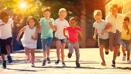 Group of happy kids running in race in the street and laughing outdoors