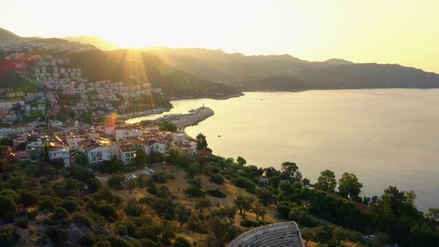 Scenic townscape and sea bay against mountains at sunset. Aerial panoramic view from drone.