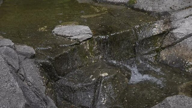 Small Waterfall running down the rocks in a city park. Greater Vancouver, British Columbia, Canada. Slow Motion