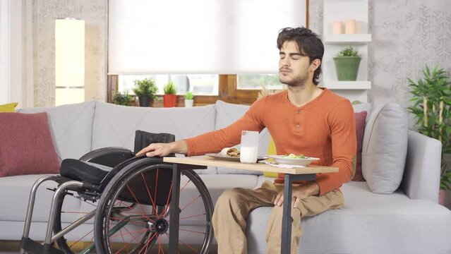 Teenager in a wheelchair is eating.
Disabled young man is happy at home and eating.
