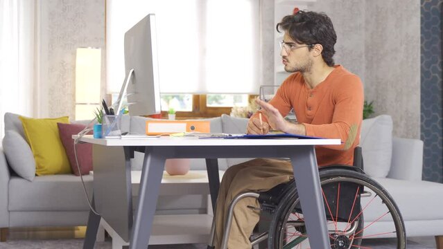 Freelance disabled businessman.
Disabled young man freelance takes notes from home and works with computer.
