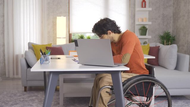 Disabled young man sitting in wheelchair making video call with laptop.
Disabled teenager sitting in a wheelchair working at his desk and making a video call with a laptop.

