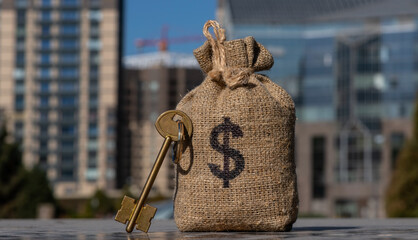 Golden key and bag with american dollar symbol on the background of modern buildings