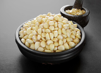 Freshly peeled garlic in the pottery and stone mortar isolated on black background.