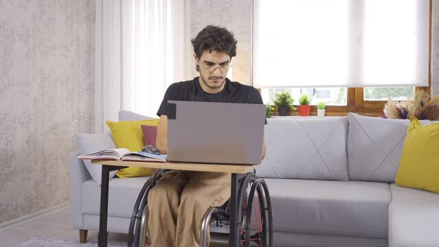 Disabled student working with laptop at home.
Disabled student working with laptop at home studying for his lessons.
