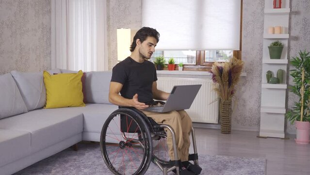 Disabled young man making a video call is at home.
Young man sitting in his wheelchair making video call on laptop.
