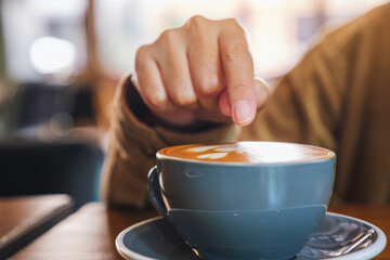 Closeup image of a hand pointing finger at a cup of hot coffee