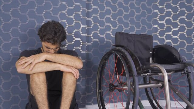 The disabled young man is unhappy and resentful of life.
Disabled man leans against a wall alone and is unhappy.
