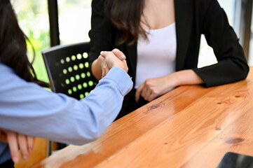 Professional Asian female worker shaking hand with her female coworker.