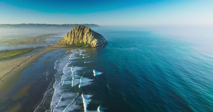 Splendid scenery of Pacific Ocean coastline with huge rock on the beach. White foamy tides coming to the shore.