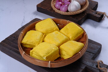 Close up of raw tahu kuning or yellow tofu in bamboo basket