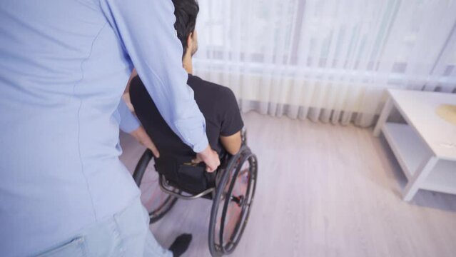 Sick disabled teenager looks out the window at home.
Teenager receiving home treatment sits in his wheelchair and looks out the window.
