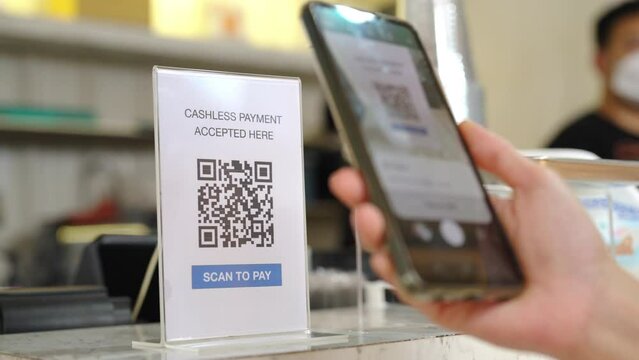 Asian woman enjoy shopping at street market on summer holiday vacation. Attractive girl using mobile phone scan QR code on bar counter making online payment buying iced coffee at outdoor coffee shop.