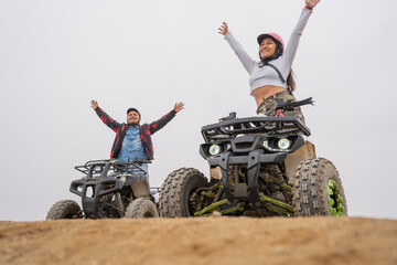 Two happy friends raising the arms on quad bikes