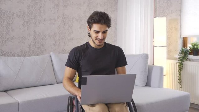 Disabled teenager making video call in slow motion.
Disabled young man working at home making video call on laptop.
