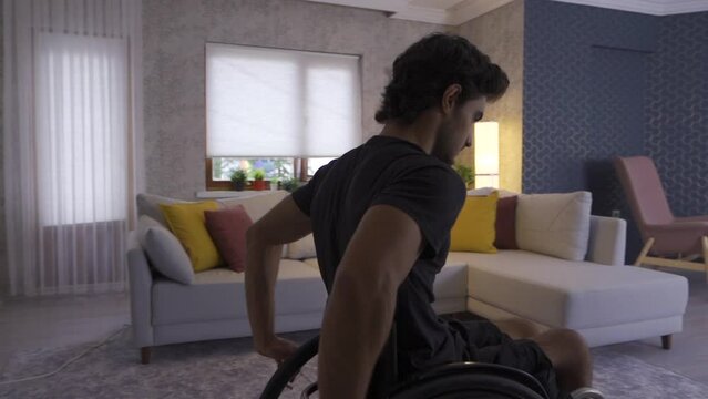 Disabled young man in wheelchair in slow motion.
Unhappy disabled young man watching out the window of the house.
