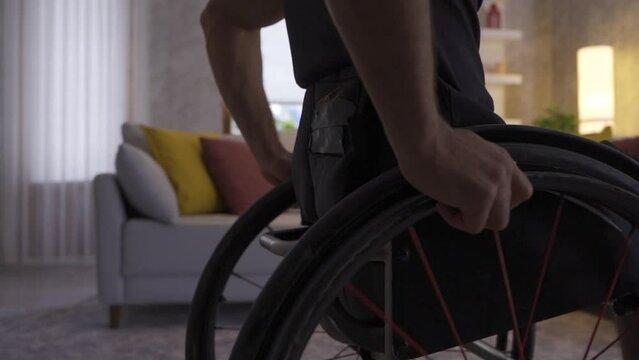 Slow motion disabled young man walking around the house in his wheelchair.
The disabled young man walking towards the edge of the window looks out the window.
