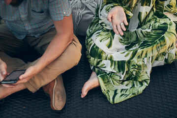 A man and a woman are sitting on a chaise longue in the park. Front view.