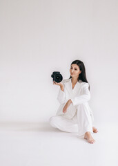 Beautiful girl photographer in a white suit with a camera. against the backdrop of a white studio. Career and education concept. Isolated