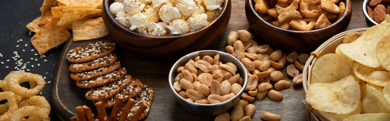Assortment of salty snacks on dark background.