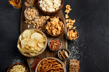 Assortment of salty snacks on dark background.