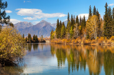 Beautiful autumn calm landscape with the Eastern Sayan Mountains and yellowed trees on the banks of the Irkut River. Baikal region, Buryatia, Tunka Valley, Nugan village