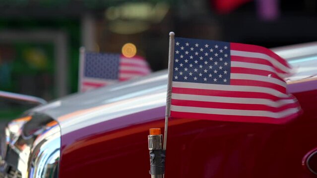 4K video with the national flag of United States of America winding in front of an iconic big American red truck.