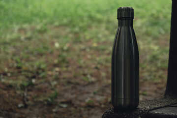 Water bottle. Reusable steel thermo water bottle on wooden bench. Sustainable lifestyle. Plastic...