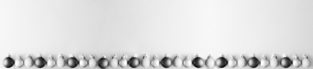 Christmas tree toys border on grey paper background. Christmas decorations on bw surface. Balls and...