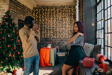 Cheerful young man and woman taking photo at home decorated for Christmas winter holiday. Happy family training together