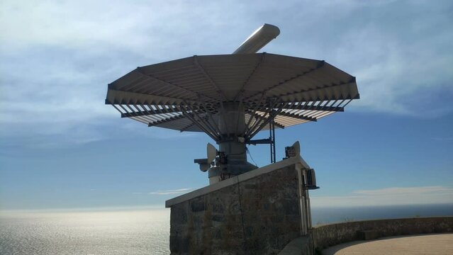 radar for maritime traffic control at the top of the mountain with the reflective sea in the background on a sunny summer day, shot blocked from below. Cíes Islands, Galicia, Spain