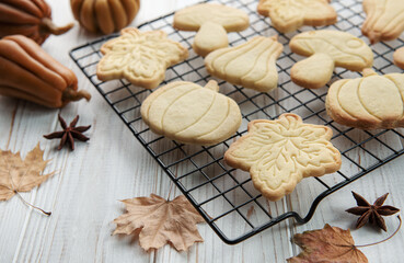 Cookies shaped like pumpkin and leaves on rustic wood background