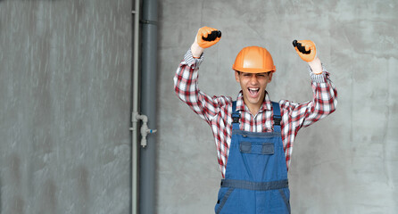 Photo of a happy positive young man builder in helmet posing isolated over gray wall background...