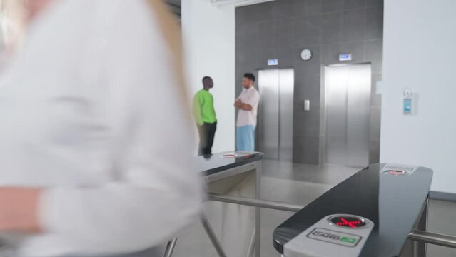 Pass system at the entrance to office building, businesswoman exit through the turnstile, elevator hall, international office.