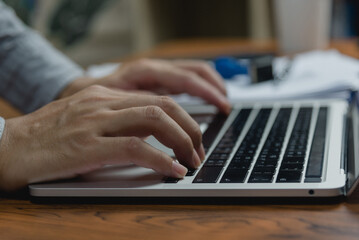 Man using computer laptop working internet searching social media and communications digital technology online at desk.