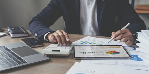 businessman writing business plan at desk in modern office. Planning analyze investment, business strategy and marketing, using graph chart and digital tablet.