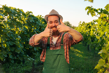 Front view looking at the camera winemaker young farmer male worker happily smiling broadly with...