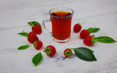 Fresh organic strawberries and black tea in glass cup , over white background. Vegetarian healthy food concept.