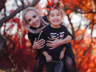 Mother and her child girl playing together. goes trick or treating. Little witch, Kids with jack-o-lantern. Children with candy bucket in fall forest. Happy Halloween.