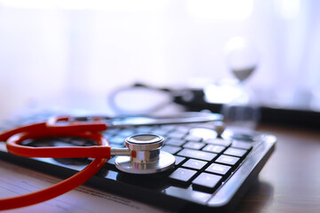 Doctor`s desk in the clinic's office. Stethoscope, test tubes, laptop, prescriptions on the table.