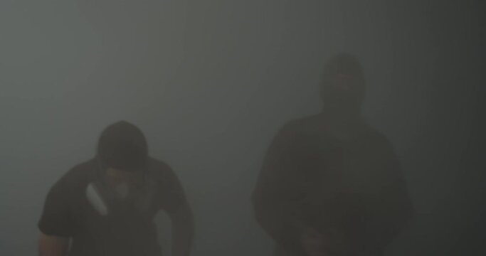 Protesters throw stones, sticks, and Molotov cocktails in the smoke.