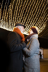 Elderly couple in love holding hands under the Christmas lights