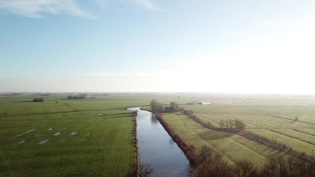 Drone shot of big landscape and a canal flowing in the middle. Beautiful top view of nature.